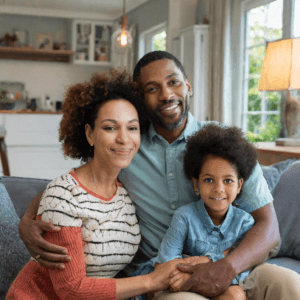 Image of a dark-skinned family in a living room of a home, a male and female adult and a child